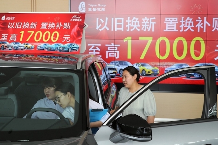 Consumers look at cars at a dealership in Dongying, Shandong province, on June 20, 2024.