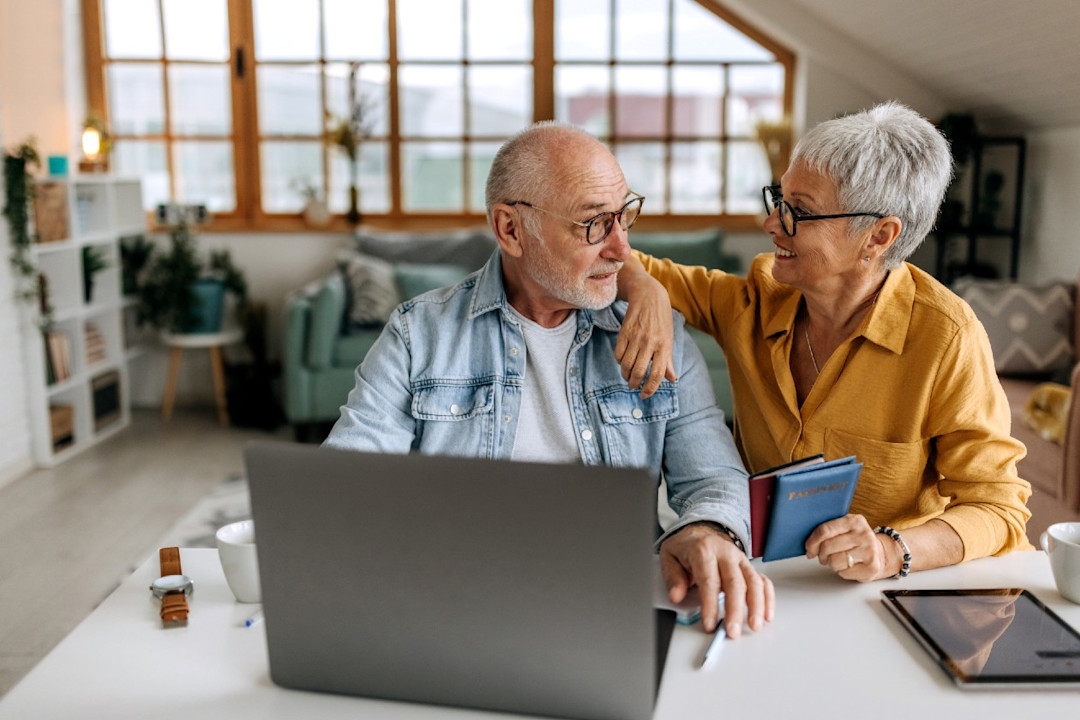 Pension age couple doing research on their laptop together in their home.jpg